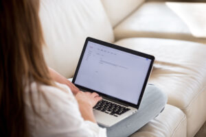 Looking over the shoulder of a woman typing on a small laptop or tablet.